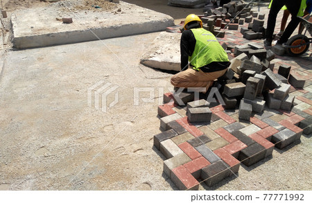 KUALA LUMPUR, MALAYSIA -MARCH 08, 2017: Construction workers installing and arranging precast concrete pavers stone for the road at the construction site.  77771992