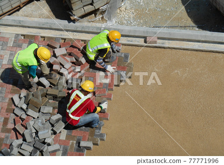 KUALA LUMPUR, MALAYSIA -MARCH 08, 2017: Construction workers installing and arranging precast concrete pavers stone for the road at the construction site. KUALA LUMPUR, MALAYSIA -MARCH 08, 2017: Construction workers installing and arranging precast concrete pavers stone for the road at the construction site. 77771996