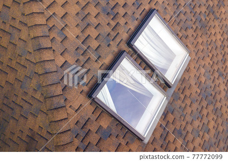 Close-up of new small attic plastic windows installed in brown shingled house roof. Professionally done building and construction work, roofing and installation concept. 77772099