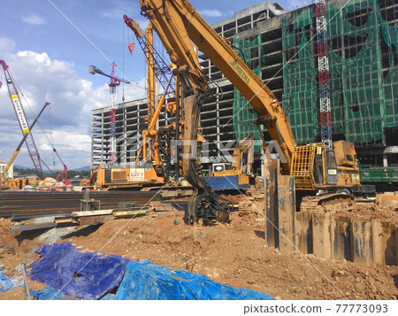SELANGOR, MALAYSIA -APRIL 15, 2016: Sheet pile cofferdam driven machine at the construction site. The machine drove the sheet pile to the earth using vibrated hydraulic arm. Workers control.  77773093