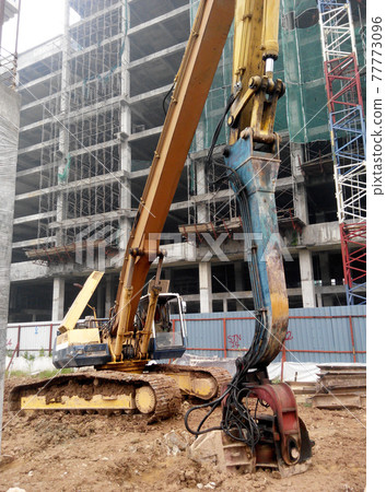 SELANGOR, MALAYSIA -APRIL 15, 2016: Sheet pile cofferdam driven machine at the construction site. The machine drove the sheet pile to the earth using vibrated hydraulic arm. Workers control.  77773096