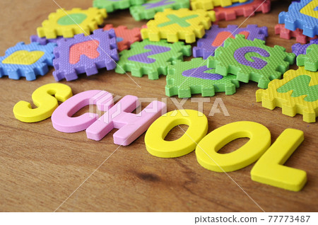 SCHOOL conceptual word made from rubber foam and colorful rubber puzzle alphabet randomly arrange. Isolated on wood texture background.   77773487