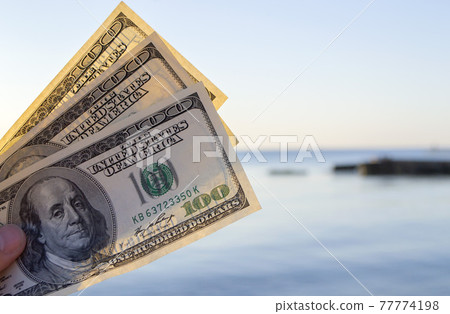 Three hundred dollar bills on background of sea surface. 100 dollar cash Three hundred dollar bills on background of sea surface. 100 dollar cash 77774198