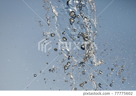 Splashes of flying water from the fountain against the blue sky Splashes of flying water from the fountain against the blue sky 77775602