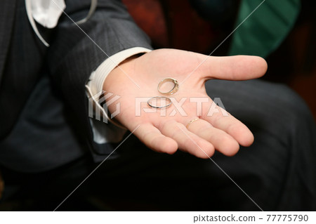 gold rings for wedding are on the palm of the groom 77775790