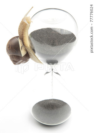 snail crawls on the hourglass. the transience of time and slowness in choosing success 77776024