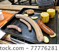 Sausages and corn grilled on the barbecue 77776281