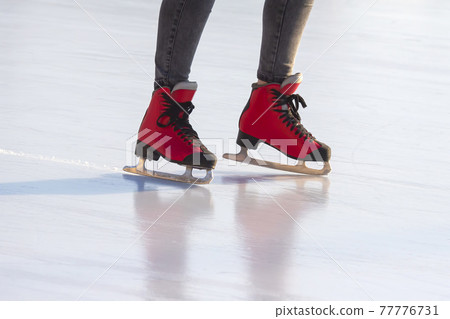 feet in red skates on an ice rink. hobbies and leisure. winter sports 77776731