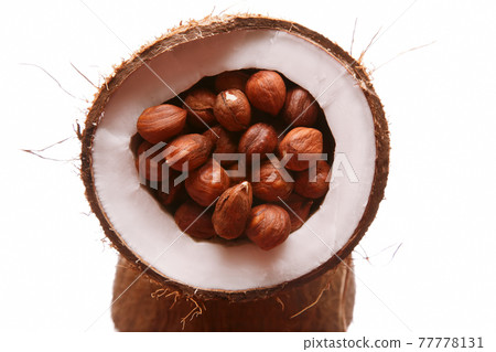 hazelnuts in a split coconut on white background 77778131