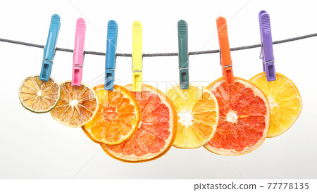 dried pieces of citrus fruits hang on clothespins 77778135