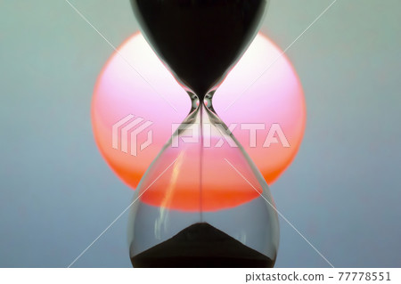 Hourglass on the background of a sunset. The value of time in life. time measuring tool Hourglass on the background of a sunset. The value of time in life. time measuring tool 77778551