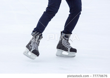 Legs of a man skating on an ice rink. Hobbies and sports. Vacations and winter activities 77778676
