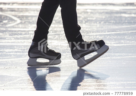Legs of a man skating on an ice rink. Hobbies and sports. Vacations and winter activities. Legs of a man skating on an ice rink. Hobbies and sports. Vacations and winter activities. 77778959