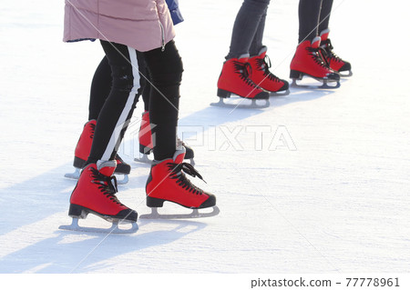 Feet of people skating on a street ice rink 77778961