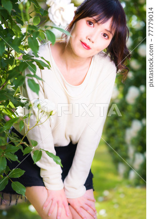 A cute girl flutters from the arch of white roses A cute girl flutters from the arch of white roses 77779014