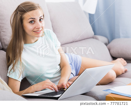 Young woman is working on sofa with laptop 77781721