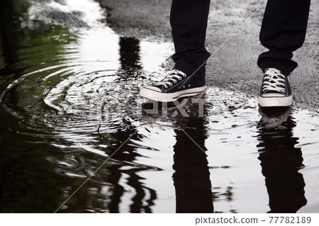 man stops with his foot in a puddle 77782189