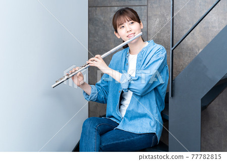 A woman blowing a flute 77782815