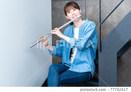 A woman blowing a flute 77782817