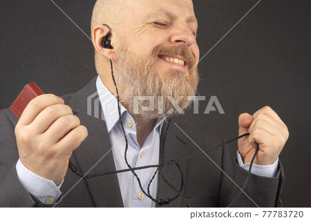 man enjoys listening to his favorite music through an audio player in small headphones 77783720