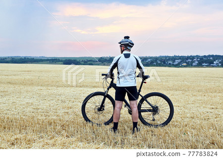 the cyclist with the bike resting on straw harvested field the cyclist with the bike resting on straw harvested field 77783824