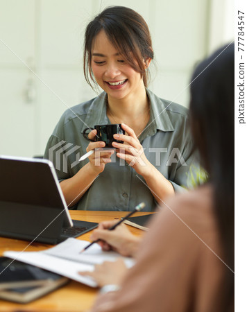 Cropped shot of female holding coffee cup and talking with coworker while meeting 77784547