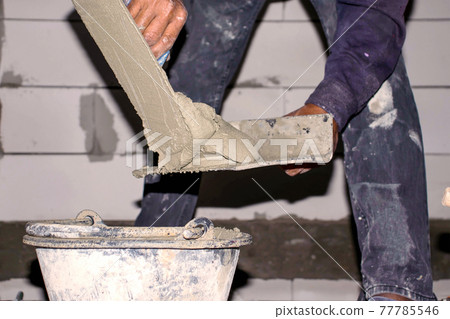 Close-up of the construction worker is mixing cement for plastering for the house and building construction. 77785546