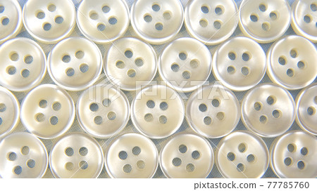 Plastic shiny buttons for clothes on a fabric background. Fashion and clothing. Factory industry 77785760