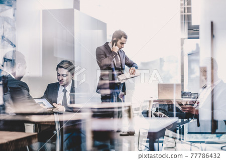 Businessman talking on a mobile phone on corporate office. Businessman talking on a mobile phone on corporate office. 77786432