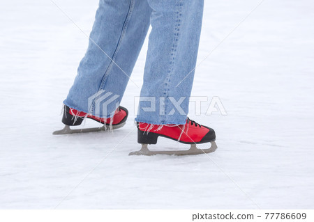 feet in red skates on an ice rink. hobbies and leisure. winter sports 77786609