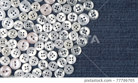 Plastic shiny buttons for clothes on a fabric background. Fashion and clothing. Factory industry Plastic shiny buttons for clothes on a fabric background. Fashion and clothing. Factory industry 77786705