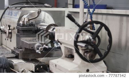 Turning lathe in action. Facing operation of metal blank on turning machine with cutting tool. Old turning lathe machine in turning workshop. Operator machining high precision mold part by cnc lathe Turning lathe in action. Facing operation of metal blank on turning machine with cutting tool. Old turning lathe machine in turning workshop. Operator machining high precision mold part by cnc lathe 77787342
