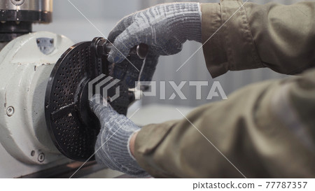 Close up hands of milling machine operator working in factory workshop. Turning lathe machine in turning workshop. Industrial theme. Metalworking and mechanical engineering. Turning lathe in action. 77787357