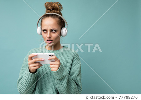 closeup photo of beautiful sad young woman wearing blue sweater isolated over blue background 77789276