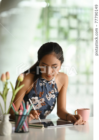 Young designer woman working with digital tablet on workplace. Young designer woman working with digital tablet on workplace. 77790149