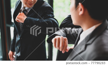 Businesspeople are greeting each other with the elbow. Elbow bumps greeting style to prevent contact and virus spread. Businesspeople are greeting each other with the elbow. Elbow bumps greeting style to prevent contact and virus spread. 77790283