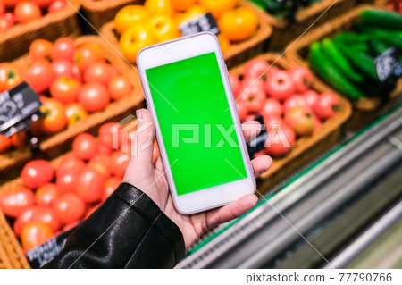 Chroma key. Close up of woman holds smart phone with green screen at grocery store. Shopping center. Department store. Mall. Shopping online. 77790766