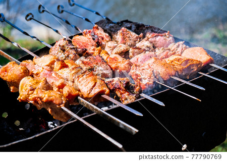 Meat is fried on coals. Camping, barbecue on the grill. Selective focus. Fried meat on charcoal BBQ 77790769