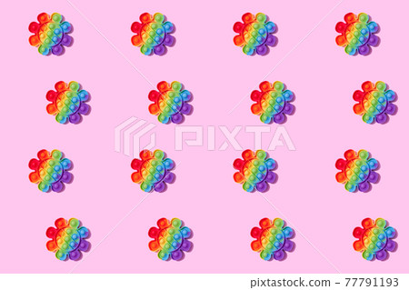 Pattern made with rainbow pop it fidget toy on pink background. Push bubble fidget sensory toy - washable and reusable stress relief toy. Antistress toy for children or adult. Mental health concept 77791193
