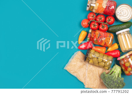 Food donations and different groceries on blue background with copy space - pasta, vegatables, canned food, baguette, cooking oil, tomatoes, cheese. Food bank, food delivery concept. Selective focus 77791202