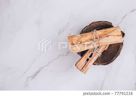 Palo Santo tree sticks inside coconut shell on light marble table background - holy incense tree from Latin America. Meditation, mental health and personal fulfilment concept. Selective focus Palo Santo tree sticks inside coconut shell on light marble table background - holy incense tree from Latin America. Meditation, mental health and personal fulfilment concept. Selective focus 77791216