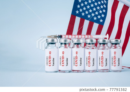 COVID-19 vaccine vials against USA flag on blue background with copy space for text - coronavirus vaccine doses, USA vaccination concept. Selective focus COVID-19 vaccine vials against USA flag on blue background with copy space for text - coronavirus vaccine doses, USA vaccination concept. Selective focus 77791382