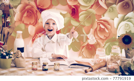 cute little baby is preparing tasty meals in the kitchen 77791919