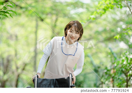 Young woman fresh green caregiver wheelchair 77791924