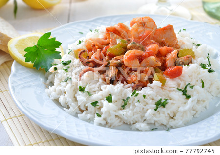 Seafood ragout with basmati rice and baguette, white wine and lemons in the background 77792745