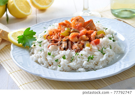 Seafood ragout with basmati rice and baguette, white wine and lemons in the background 77792747