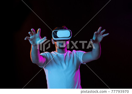 Young man's portrait on black studio background in neon light. Concept of human emotions, facial expression, youth, sales, ad. 77793970