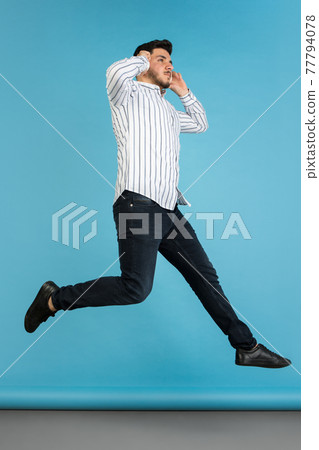 Young man's portrait on blue studio background. Concept of human emotions, facial expression, youth, sales, ad. 77794078
