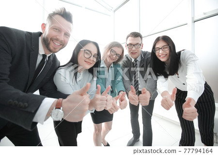 smiling business team looking at the camera and showing thumbs up smiling business team looking at the camera and showing thumbs up 77794164