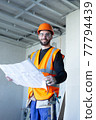 Male worker holding a paper apartment plan indoor before repair room  77794439
